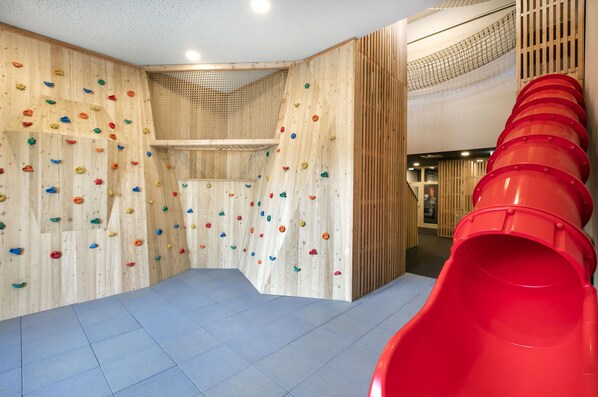 A climbing wall with various holds and a red slide. - JUFA Hotel Weiz (Weiz)