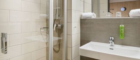A modern bathroom with a glass-enclosed shower, a white sink, and a mirror above it.