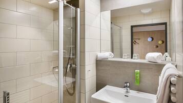 Une salle de bain moderne avec une douche à parois de verre, un lavabo avec un miroir et un porte-serviettes.