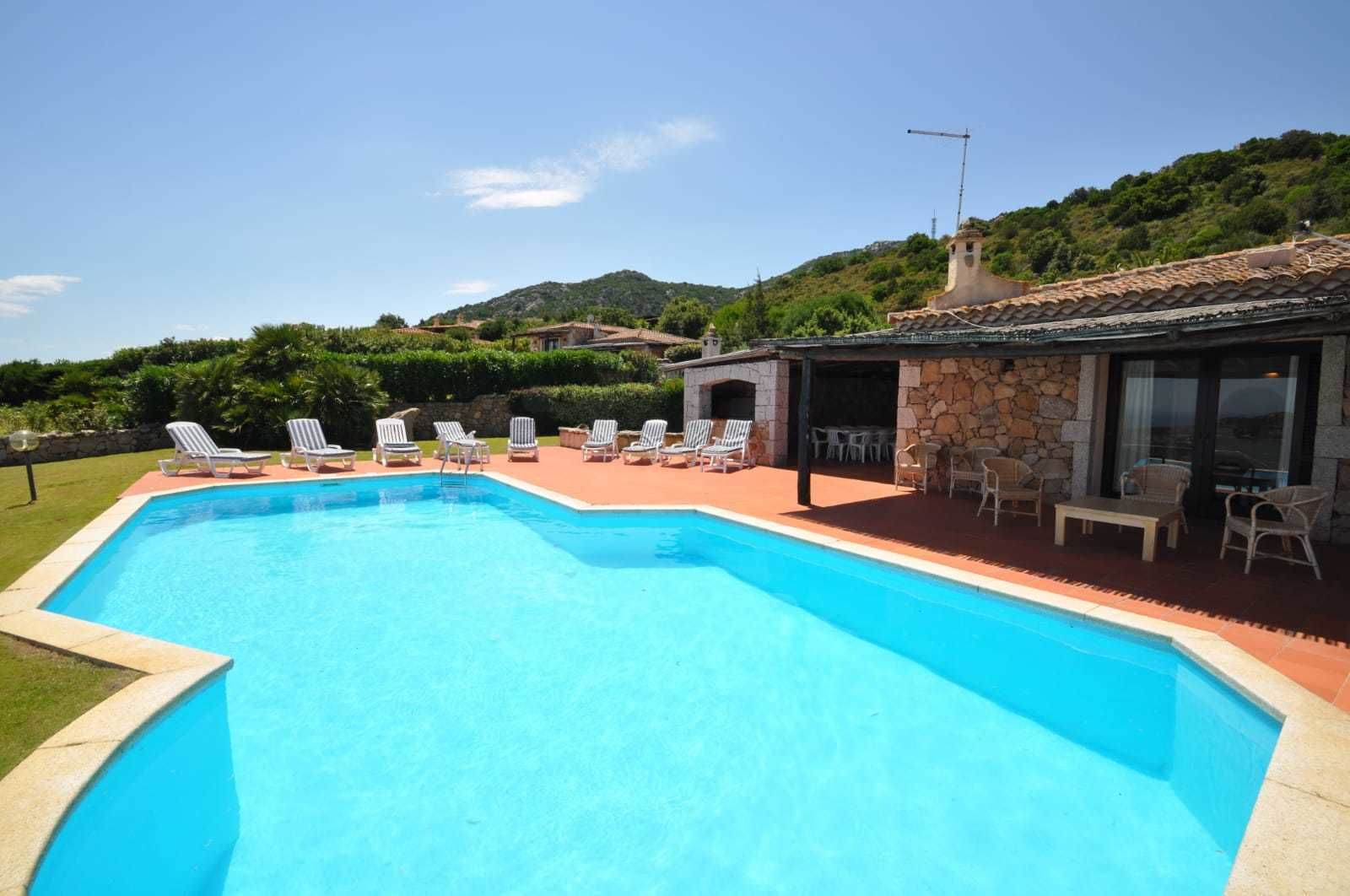 A swimming pool with lounge chairs and a stone building with outdoor seating.