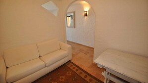 A room with a white sofa, a small table, and a patterned rug. - Villa Lara 3 (Arzachena)