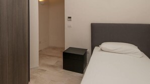 Ein Schlafzimmer mit einem Bett, einem Nachttisch, einer Wandleuchte und einer Tür zu einem Badezimmer.