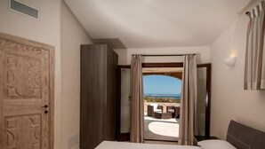 Ein Schlafzimmer mit einem großen Bett, Blick ins Freie und einer Tür zu einem Balkon.