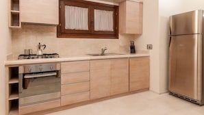 A modern kitchen with a built-in oven, a stainless steel refrigerator, and wooden cabinets.