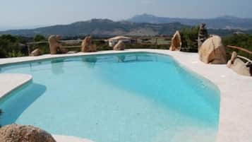 Una piscina al aire libre de temporada, sillones reclinables de piscina