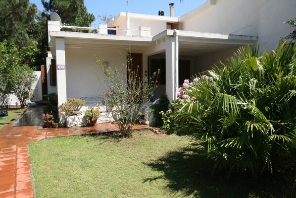 A modern house with a covered patio, a small garden, and a satellite dish.