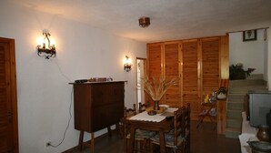 Un coin repas comprenant une table en bois, des chaises, un buffet et un téléviseur.