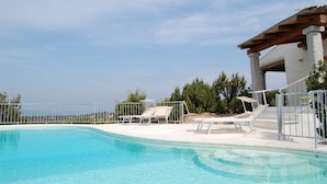 Une piscine dotée de chaises longues et d’une structure en forme de pergola.