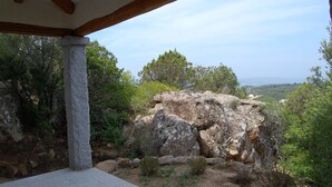 Un pilier de pierre et une structure en poutres de bois, offrant une vue sur un paysage rocheux et des arbres.