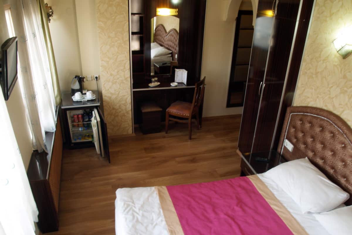 Una habitación de hotel con una cama, un escritorio, una silla y un armario.