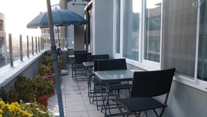 A balcony with outdoor seating, potted plants, and a view of the city. - Grand Hotel Duman (Ankara)