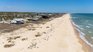 Ein Küstenwohngebiet mit Strandhäusern, Sandstrand und Blick auf den Ozean.