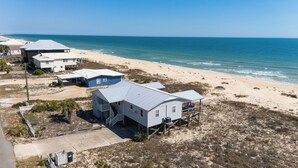 Ein Strandgrundstück mit mehreren Häusern, darunter ein Haupthaus mit Balkon und ein kleineres Gebäude.