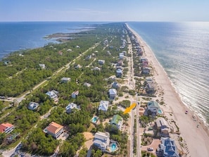 An aerial view of a coastal residential area with houses, a beach, and a clear view of the ocean. - Let your dreams come true in Once Upon A Tide! (Eastpoint)