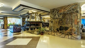 A spacious lobby with a stone fireplace, seating area, and a bar.