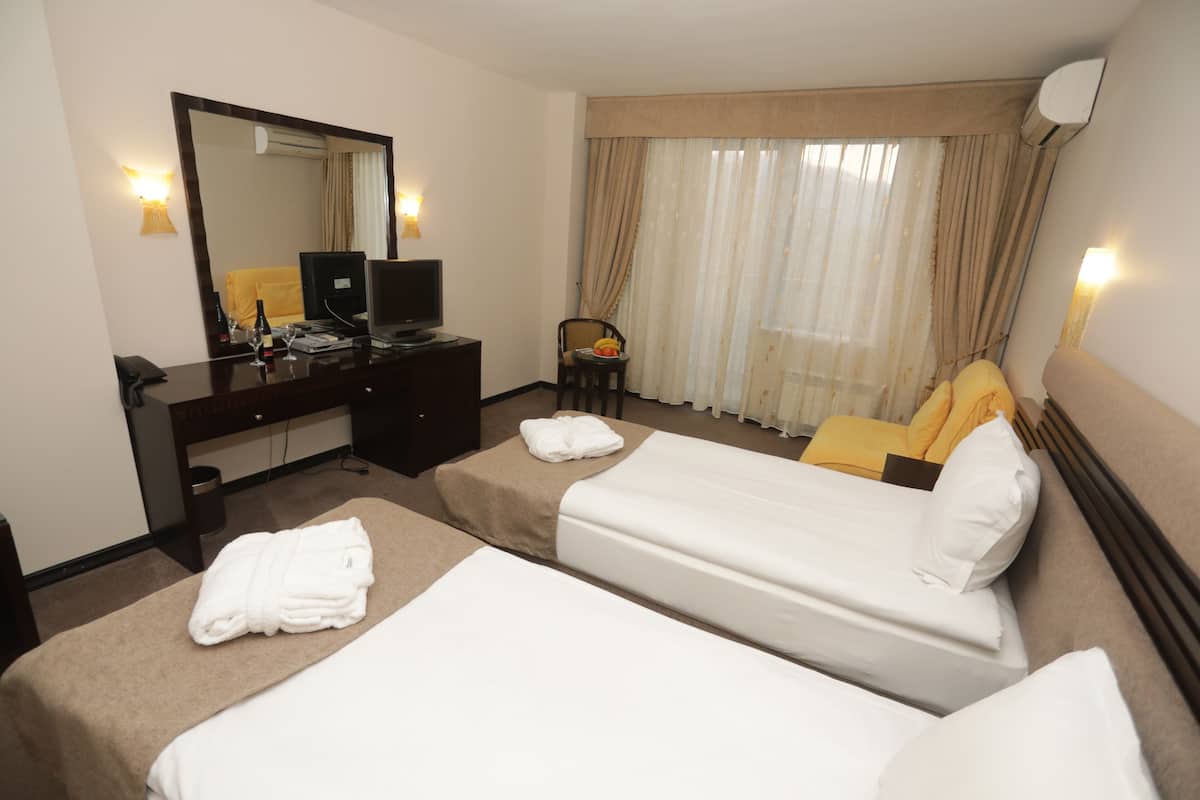 A hotel room with two beds, a desk with a computer, a chair, and a large mirror.
