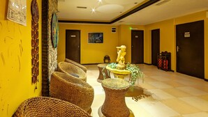 A hotel lobby with yellow walls, wicker furniture, a fountain, and a map on the wall.