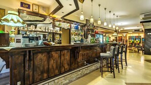 A bar area with a wooden counter, bar stools, and a variety of bottles and glasses.
