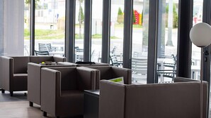 A modern indoor seating area with cushioned booths and a small table, large windows with a view of the outside. - Hotel Lika Sjever (Brinje)