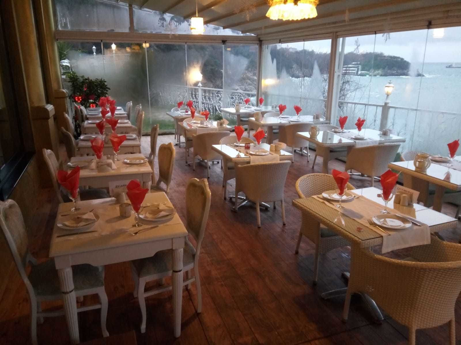 A restaurant with tables set for dining, featuring wicker chairs and white table settings.