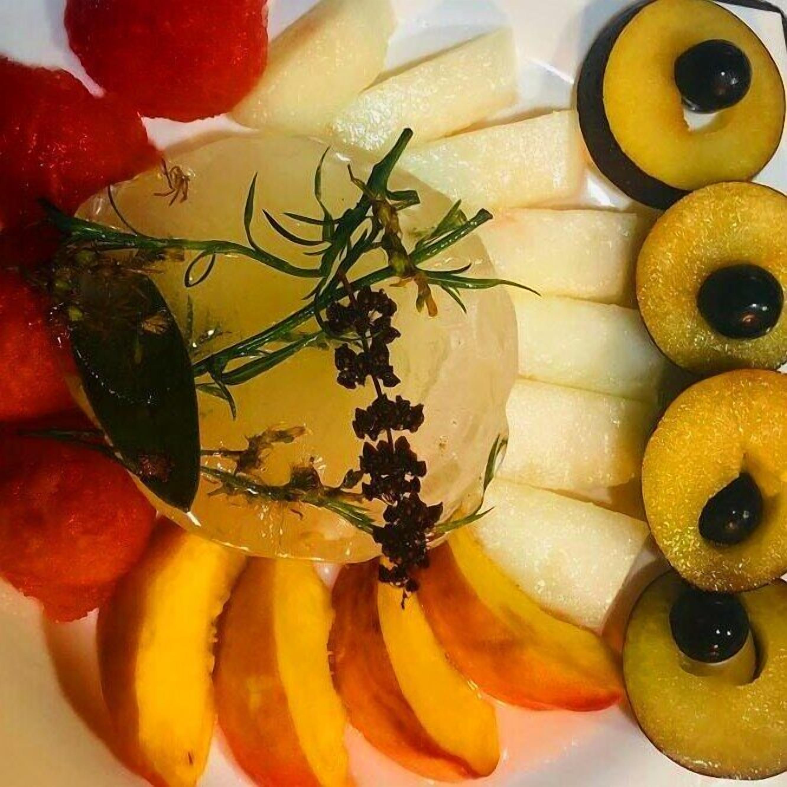 Una bandeja de frutas con melocotones, manzanas y un centro de mesa de vidrio decorativo.
