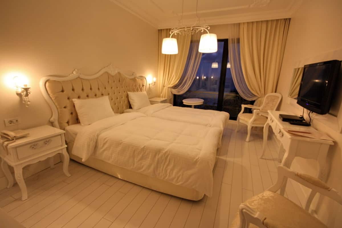 A hotel room with a large bed, a TV, a desk, and a chair.