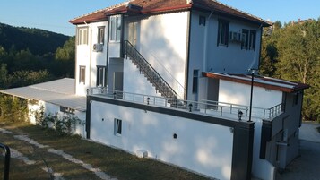 Una casa moderna de dos pisos con una escalera que lleva al nivel superior, un balcón y un pequeño garaje adosado.