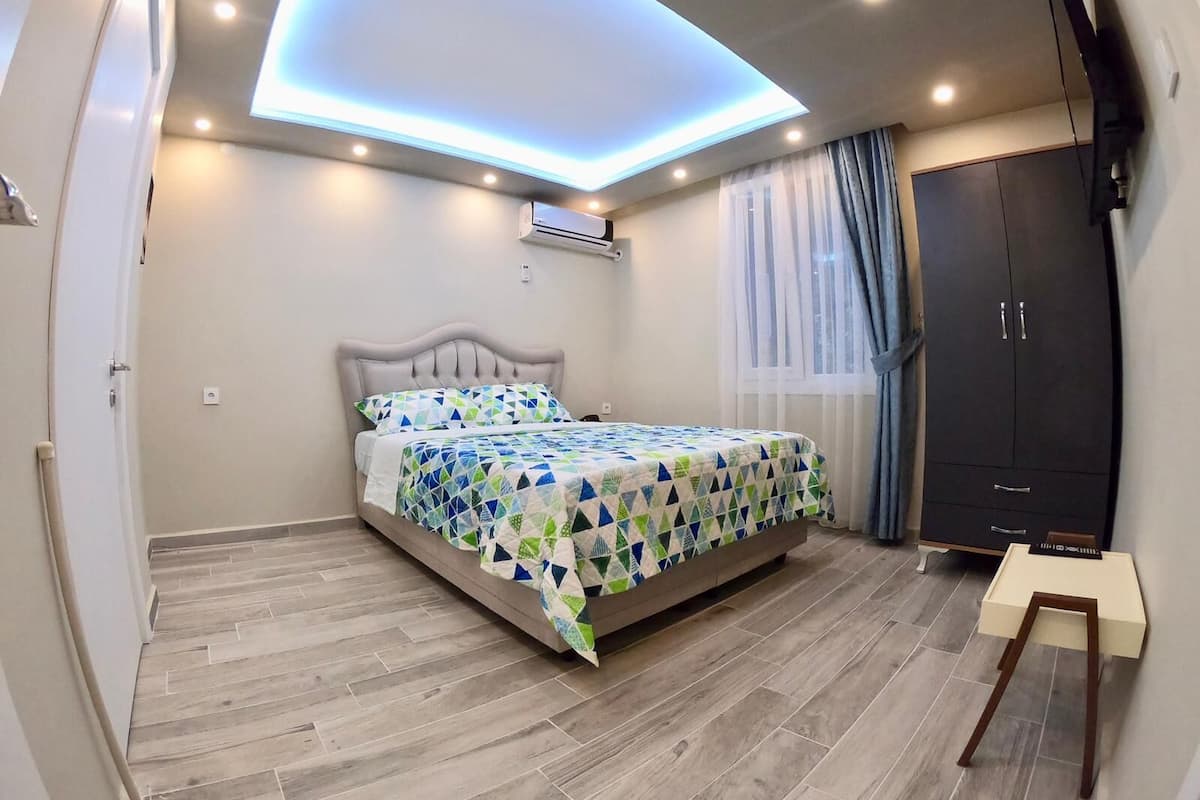 Ein Schlafzimmer mit einem Bett, einem Kleiderschrank, einer Deckenleuchte und einer Klimaanlage.