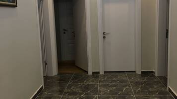A hallway with dark marble flooring, white doors, and recessed ceiling lighting.