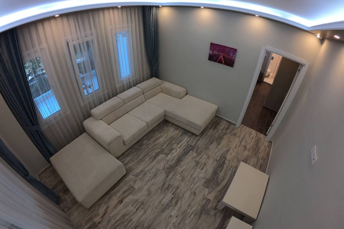 Ein modernes Wohnzimmer mit einer Eckcouch, einem kleinen Tisch und einer Tür zu einem anderen Raum.