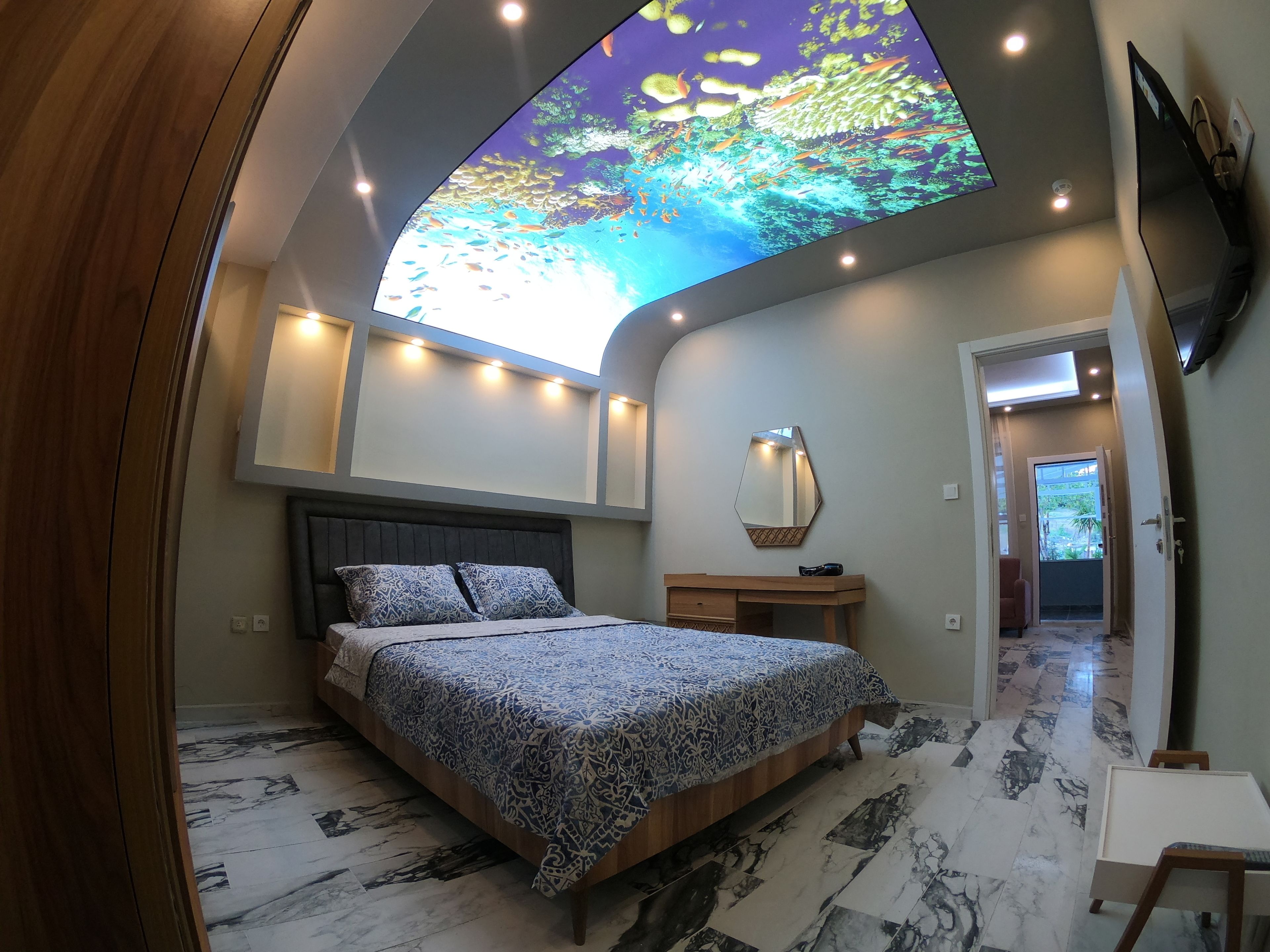 A bedroom with a bed, bedside table, and a ceiling projection.