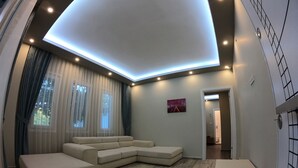 Una sala de estar moderna con un sofá modular, una mesita y un techo con iluminación empotrada.