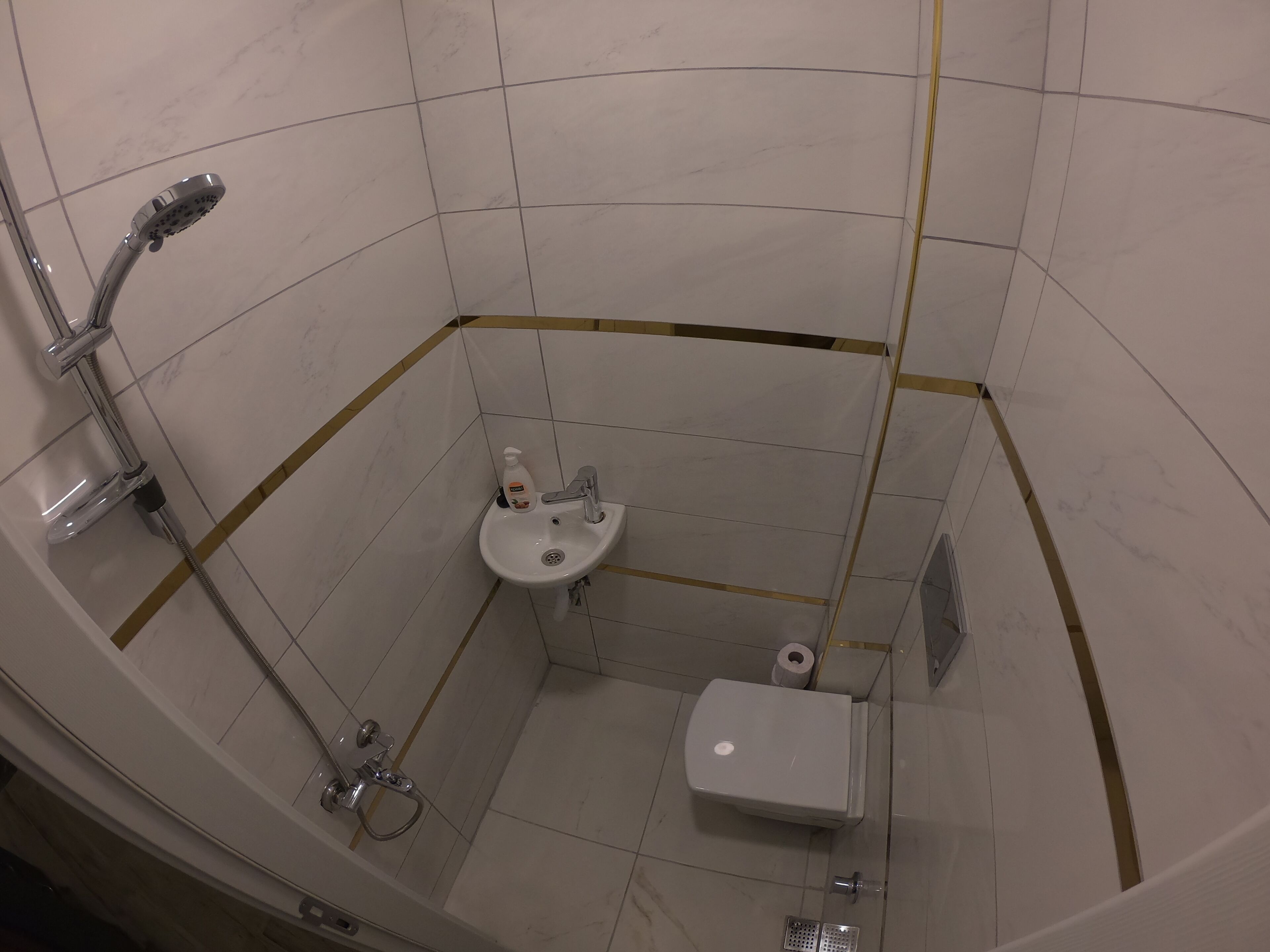 A small, compact bathroom with a shower, sink, and toilet.