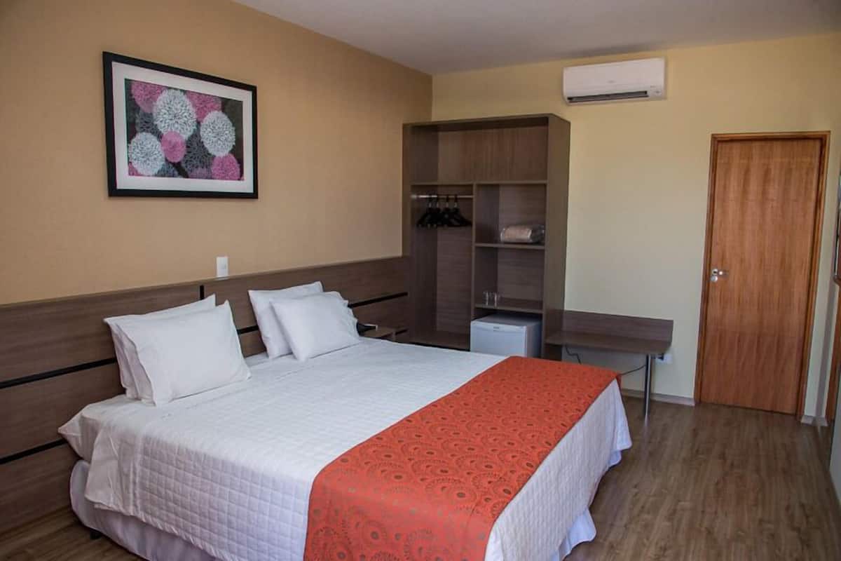Une chambre d’hôtel avec un lit, une armoire, un bureau et une porte.