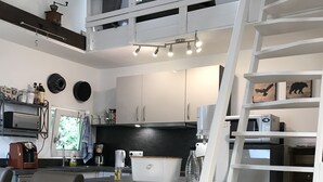 Une cuisine moderne dotée d’un îlot central, de meubles blancs, d’un four à micro-ondes encastré et d’une machine à café.