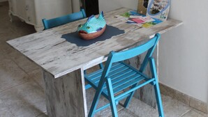 A dining area with a rustic wooden table, a blue chair, and a decorative fish bowl. - Typical Ostuni House - Free WiFi - Mini Spa (Ostuni)