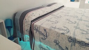A neatly made bed with striped bedding and a nautical-themed duvet cover. - Typical Ostuni House - Free WiFi - Mini Spa (Ostuni)
