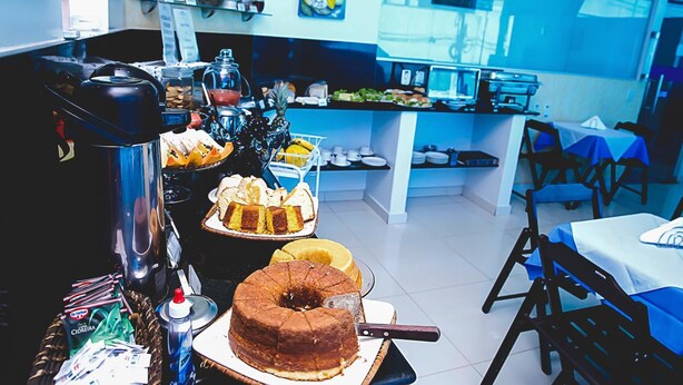 A breakfast buffet with various cakes and pastries, a coffee station, and seating arrangements. - Bellonorte Hotel (Altamira)
