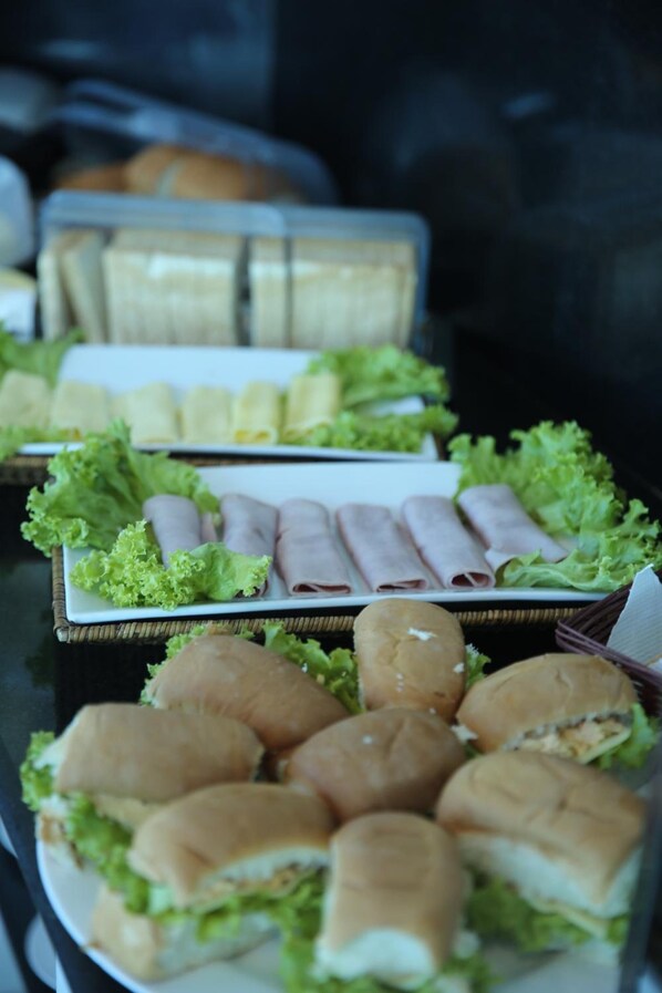 A buffet table with various food items including sandwiches, rolls, and salads.