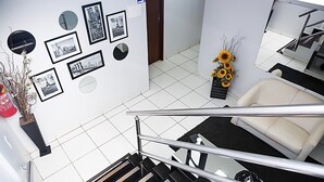 A hotel lobby with a staircase, a reception desk, framed pictures on the wall, and a sofa. - Bellonorte Hotel (Altamira)