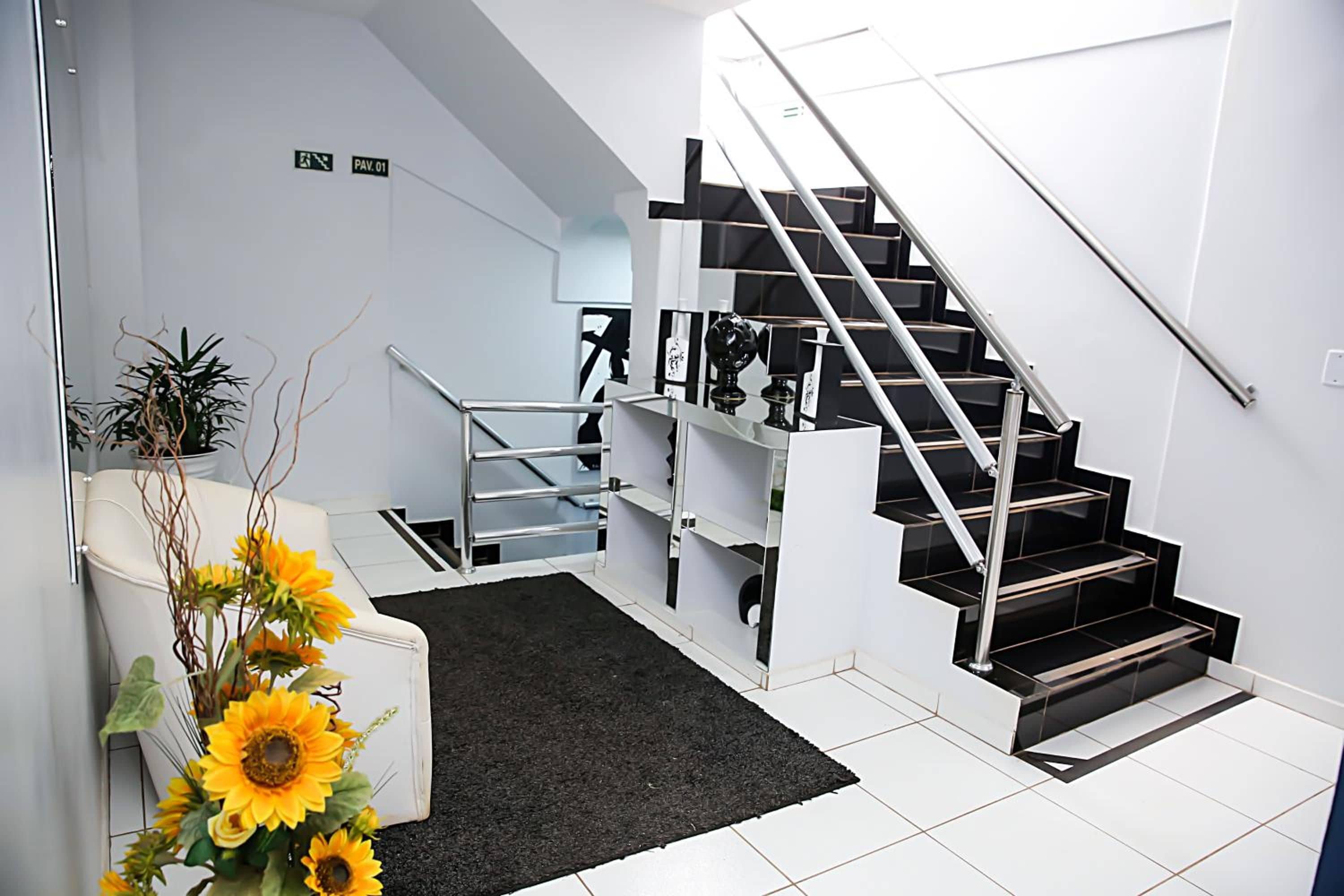 Un interior moderno con una escalera, una alfombra negra y un sofá blanco con un arreglo de girasoles.