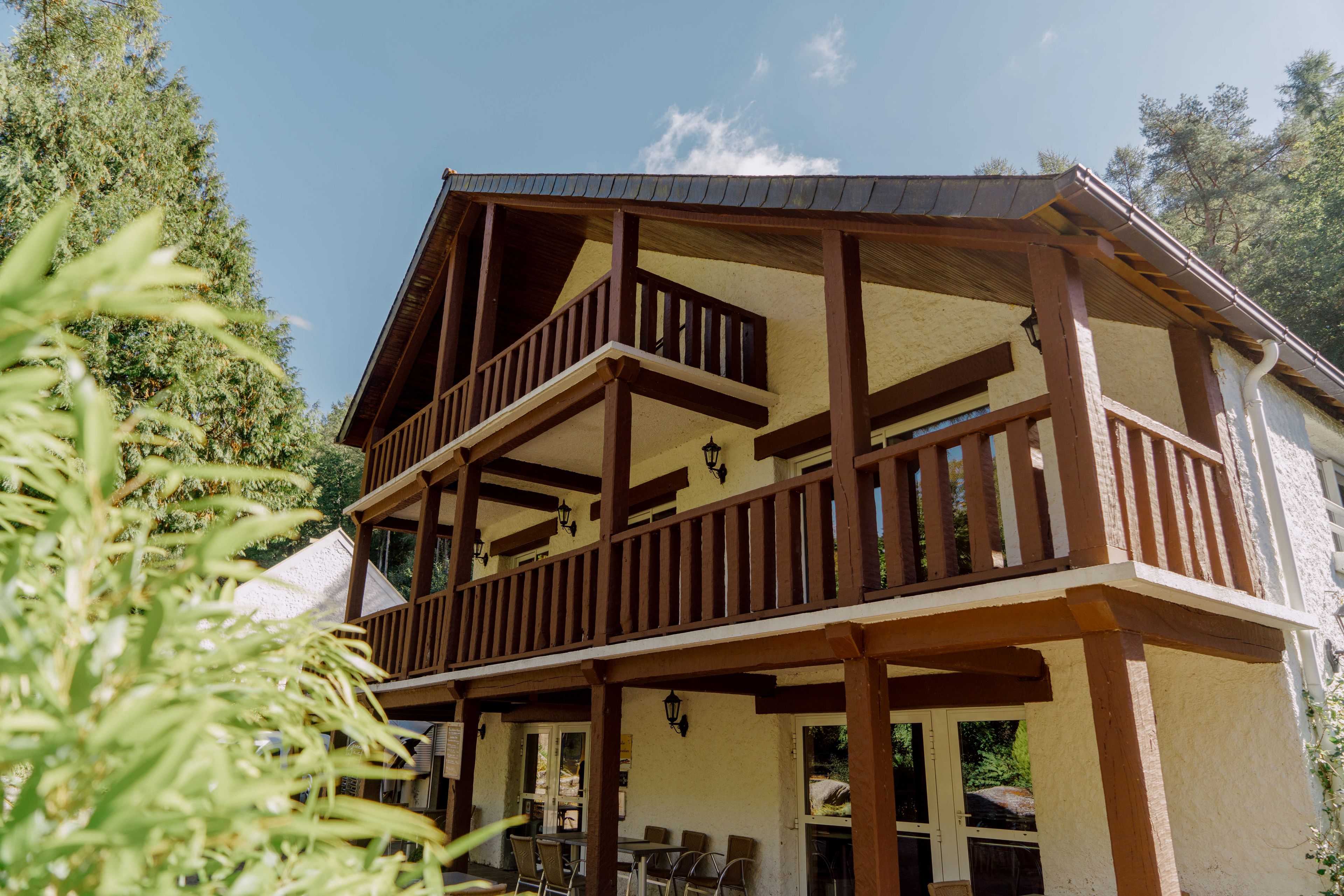 A two-story wooden building with balconies and a covered patio area.