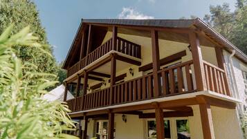 A two-story wooden building with balconies and a covered patio area.