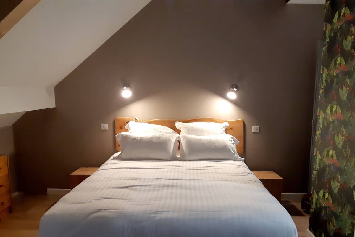 Une chambre à coucher avec un grand lit, deux tables de chevet et un plafond en pente.