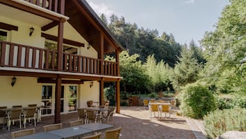 A building with a wooden balcony and outdoor seating area with tables and chairs.