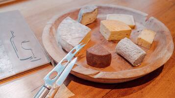 Een houten bord met verschillende kazen en een kaasmes op een houten tafel.