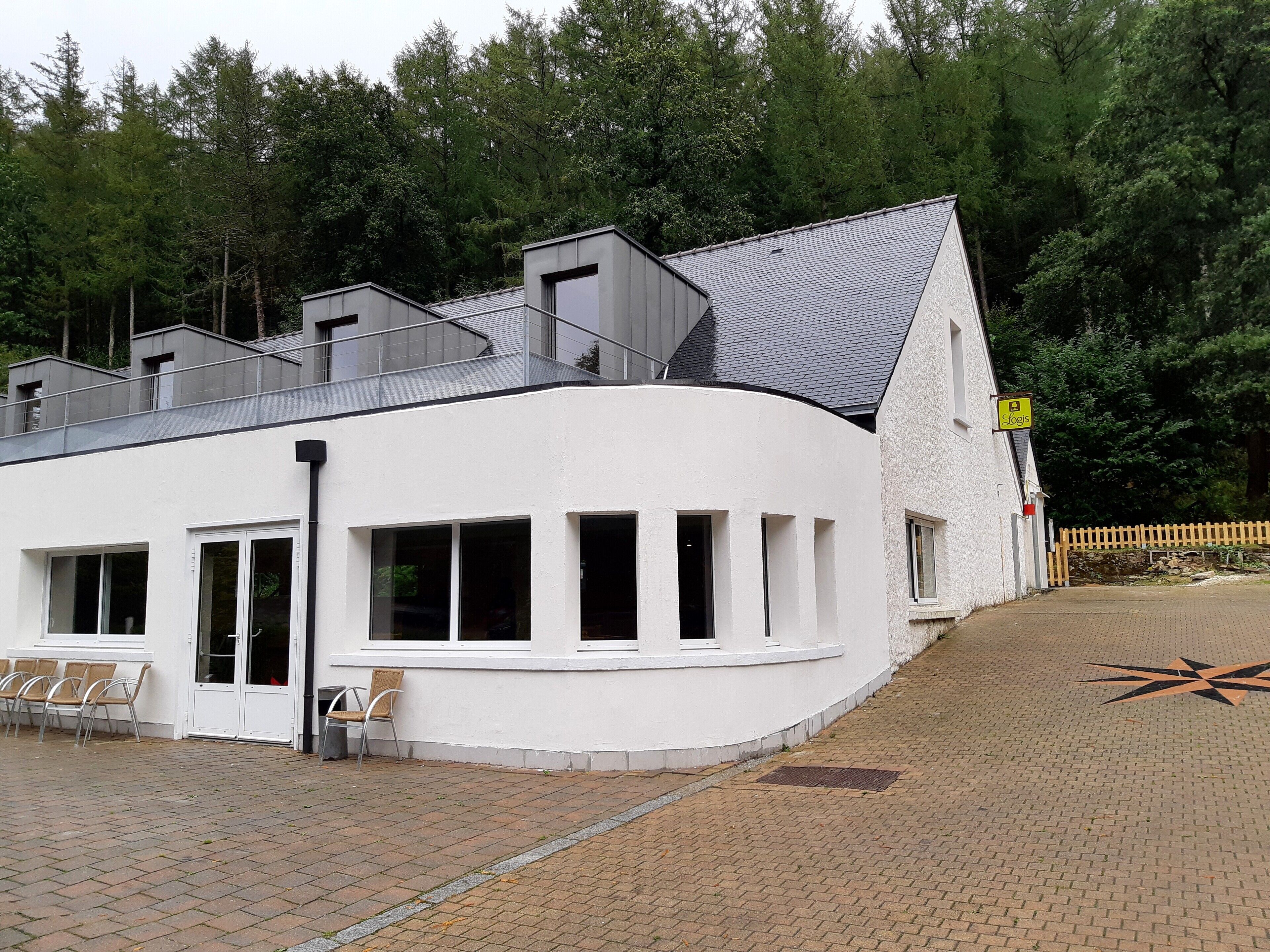 A modern building with a white exterior, multiple windows, and a sloped roof.