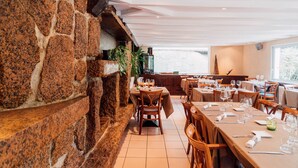 A restaurant with stone walls, wooden tables, and chairs.