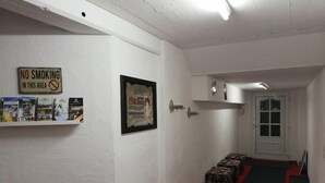 Un passadís amb un cartell de 'No Fumar', un pòster emmarcat de Coca-Cola, una estant amb llibres i una escala amb otomans estampats.