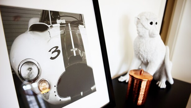 A framed photograph of a vintage race car on a table with a small figurine and a copper mug. - Plenus Riverloft (Bremen)